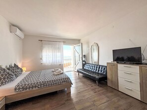 Ett sovrum med en säng, en soffa, en tv och en byrå.