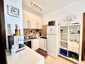 Een koelkast, een magnetron, een oven, kookgerei, borden en bestek