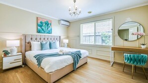 A bedroom with a large bed, bedside tables, a dresser, a mirror, and a window with blinds. - StayAU Comfortable House w/Pool Table & Backyard (Corio)