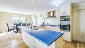 A modern kitchen with a blue countertop, white cabinets, and stainless steel appliances. - StayAU Comfortable House w/Pool Table & Backyard (Corio)