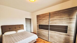 A bedroom with a bed, a wardrobe, and a wooden herringbone floor. - in Crikvenica mit Meerblick by Interhome (Crikvenica)