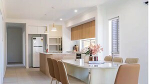 Une cuisine moderne dotée d’un îlot central, de meubles blancs et d’un coin repas avec des chaises.