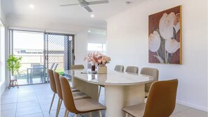 Un coin repas avec une table ronde, six chaises et un ventilateur de plafond.