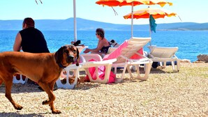 A beach with umbrellas, chairs, and a dog. - Schöne Erdgeschosswohnung mit Sonnenterrasse by Interhome (Crikvenica)