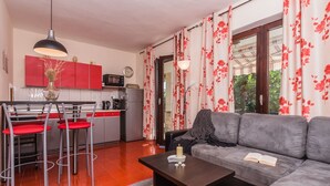A compact living space with a kitchenette, a dining area with red chairs, a grey sofa, and a striped rug. - Schöne Erdgeschosswohnung mit Sonnenterrasse by Interhome (Crikvenica)