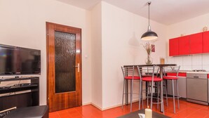 A modern living room with a TV, a wooden door, a dining area with red chairs, and a kitchen with red cabinets. - Schöne Erdgeschosswohnung mit Sonnenterrasse by Interhome (Crikvenica)