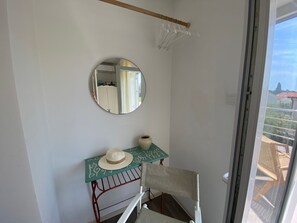 Ein Zimmer mit Spiegel, einem kleinen Tisch mit Hut und einem Stuhl.