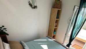 A cozy room with a bed, a wooden shelf, and a view through a window. - Luxus Ferienhaus AmbraLore by Interhome (Krk/Krk)