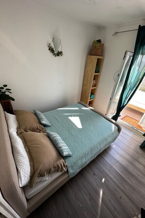 Ein gemütliches Zimmer mit einem Bett, einer Holzablage und Blick durch ein Fenster.