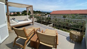 A balcony with a bed, wicker chairs, and a canopy. - Luxus Ferienhaus AmbraLore by Interhome (Krk/Krk)