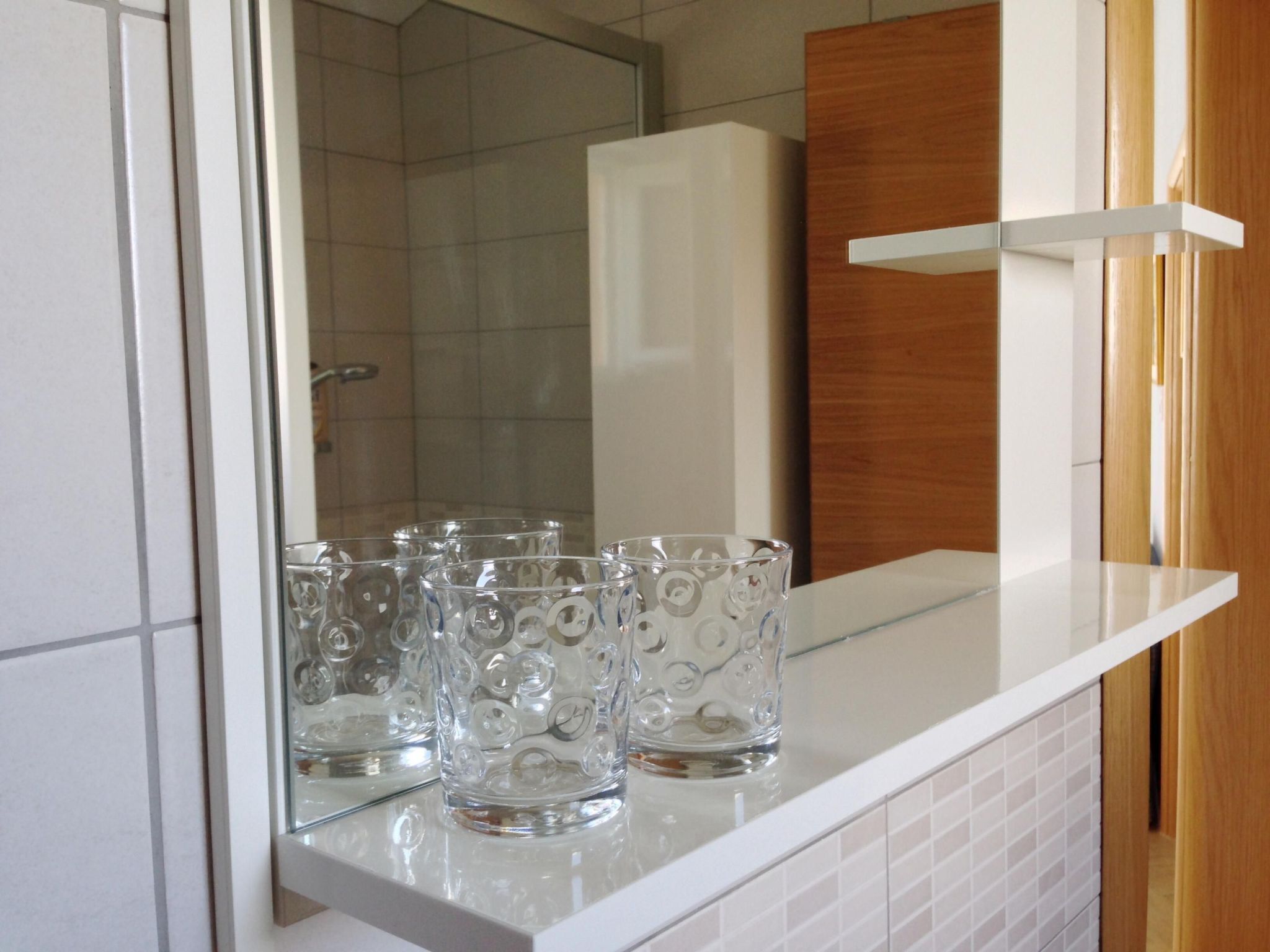 Una encimera de cocina con vasos de vidrio transparente y un refrigerador blanco.