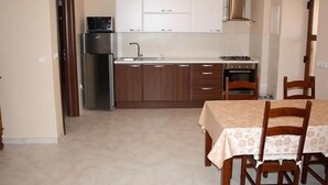 Eine kleine Küche mit Kühlschrank, Herd, Spüle und Holzschränken.
