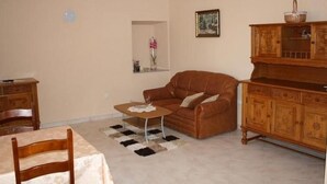 Ein Wohnzimmer mit einer braunen Ledersofa, einem Holzschrank und einem Esstisch mit Stühlen.