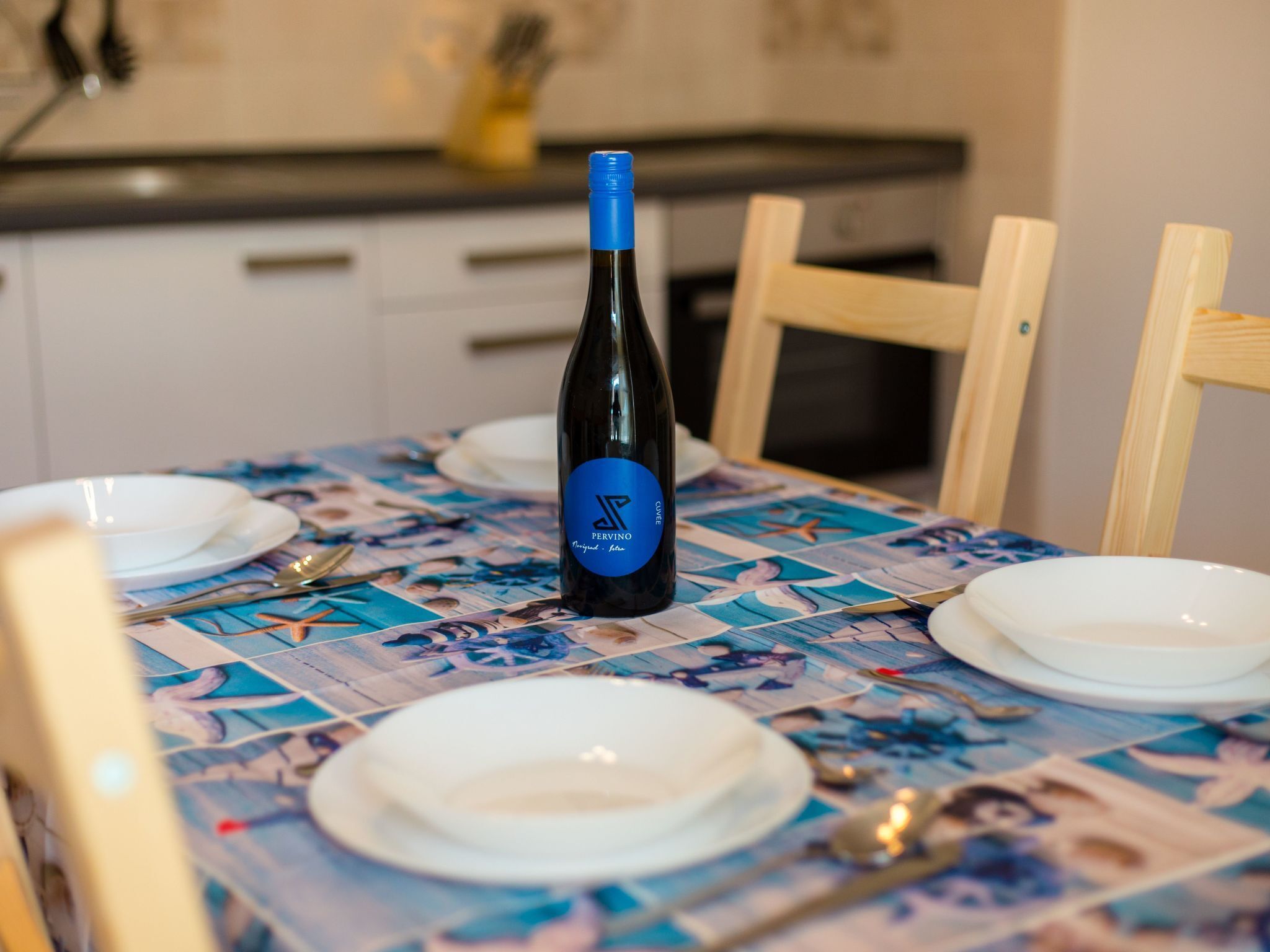 Une table à manger avec une bouteille de vin, des assiettes et des couverts.