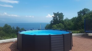 Een achthoekig whirlpoolbad met een helder uitzicht op zee en begroeiing op de achtergrond.