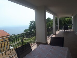 A balcony with a table and chairs, overlooking a scenic view of the sea and greenery. - Charmante Wohnung Adriana F by Interhome (Lovran)