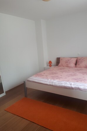 A bedroom with a bed, a nightstand, a lamp, and an orange rug. - Charmante Wohnung Adriana F by Interhome (Lovran)