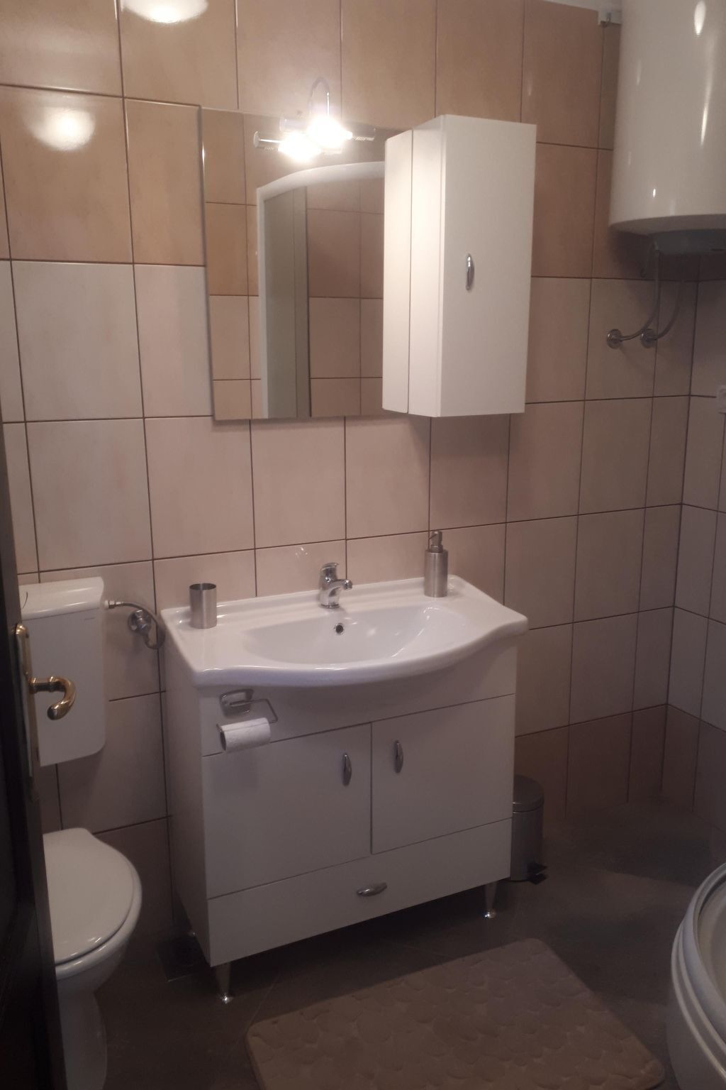 Un baño con lavamanos blanco, inodoro, armario y espejo.