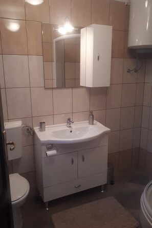 A bathroom with a white sink, a toilet, a cabinet, and a mirror. - Charmante Wohnung Adriana F by Interhome (Lovran)