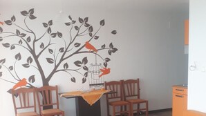 Een woonkamer met een bank, stoelen, een bijzettafeltje en een wanddecoratie.