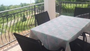En balkon med et bord og stole, der udover et grønt landskab.