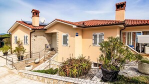 Ein Haus im mediterranen Stil mit Ziegeldach, Steinmauern und einer Steintreppe, die zum Eingang führt.