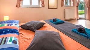 Hotellihuone, jossa on sänky, tyynyjä, joogamatto ja verhot.