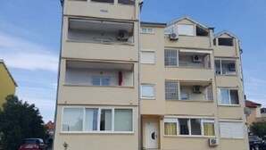 A multi-story residential building with balconies, air conditioning units, and a garage. - in Medulin mit Privatparkplatz by Interhome (Medulin)