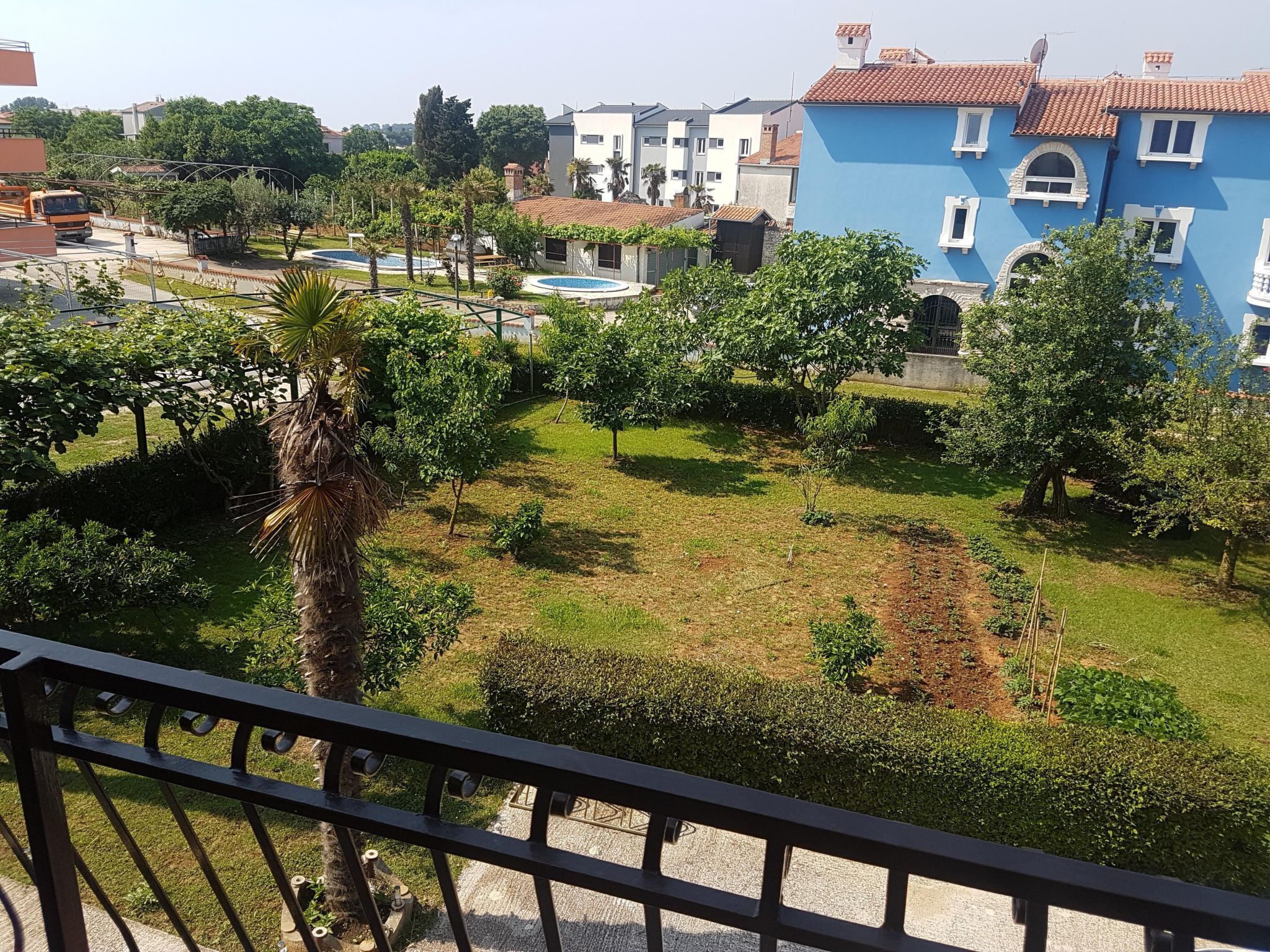 A residential area with a blue building, a swimming pool, and a well-maintained garden.