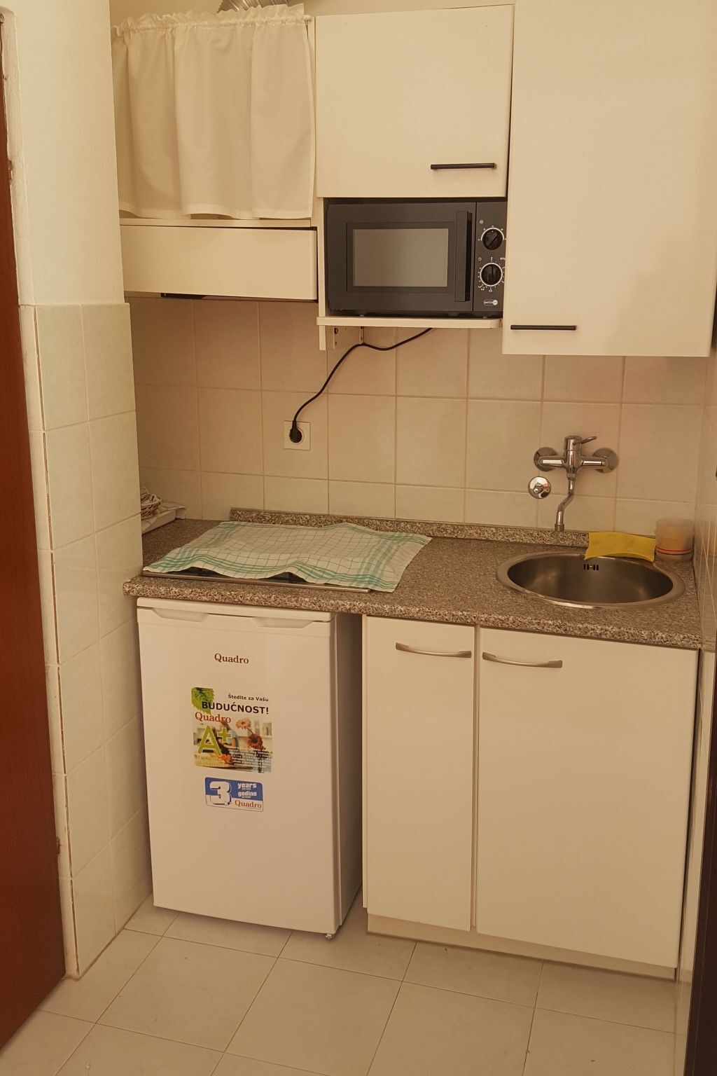Eine kleine Küche mit Mikrowelle, Spüle und kleinem Kühlschrank.