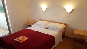 A neatly made bed with a red blanket and a folded towel, two bedside tables with lamps, and a wooden floor. - Attraktiver Standort by Interhome (Medulin)
