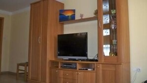 A wooden entertainment unit with a flat-screen TV, shelves, and a glass-fronted cabinet. - mit Blick auf das Wasser by Interhome (Pula/Banjole)