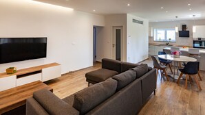 Un soggiorno moderno con una grande TV a schermo piatto, un divano e un'area pranzo con tavolo e sedie.