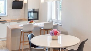 Una cucina moderna con forno integrato e zona pranzo con tavolo e sedie rotonde.