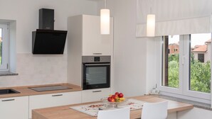 Una cucina moderna con forno integrato, cappa aspirante nera e una finestra vista verde.