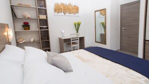 Ein Schlafzimmer mit einem großen Bett, einem Schreibtisch, einem Stuhl, einem Bücherregal und einem Kleiderschrank.