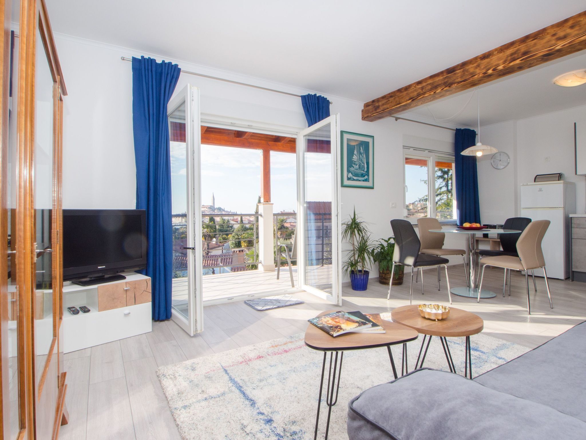 Una sala de estar moderna con una televisión de pantalla plana, un sofá, una mesa de centro y un comedor con sillas y una mesa.