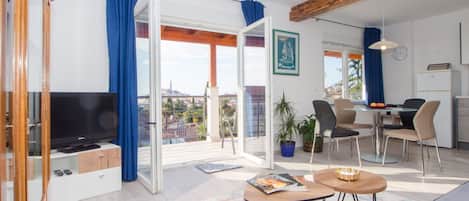 Una sala de estar moderna con una televisión de pantalla plana, un sofá, una mesa de centro y un comedor con sillas y una mesa.
