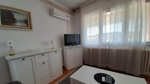 A small, clean room with white furniture, a TV, and a painting on the wall. - Helle und luftige Ferienwohnung in erster Reihe zum Meer, mit einem privaten Ba by Interhome (Rovinj)