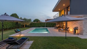 A modern outdoor pool area with lounge chairs and umbrellas, a stone wall, and a well-maintained lawn. - in Dračevac mit Großem Pool by Interhome (Dracevac)