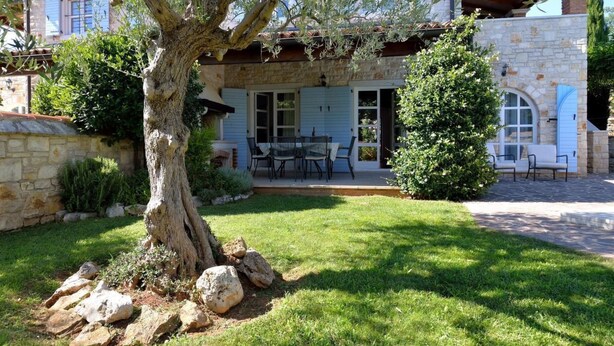 A stone house with a patio, outdoor seating, and a large tree in the yard. - Villa Maslinova Grana by Interhome (Poreč/Tar)