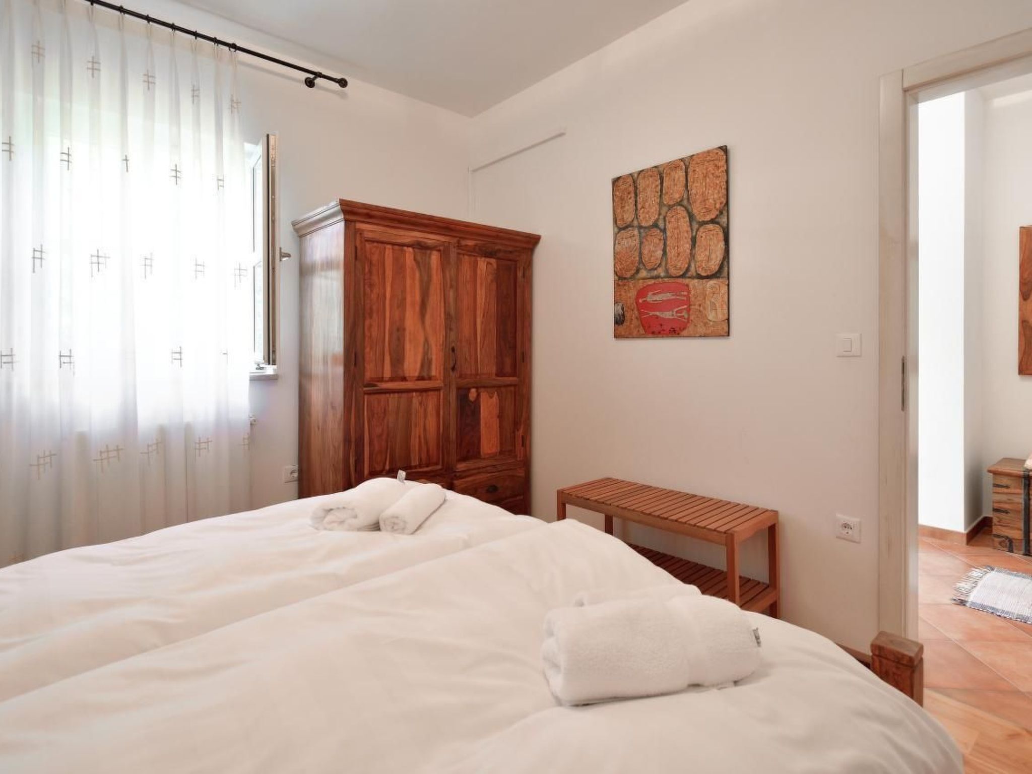 Ein Schlafzimmer mit einem großen Bett, einem Holzschrank, einem kleinen Tisch und einem Bild an der Wand.