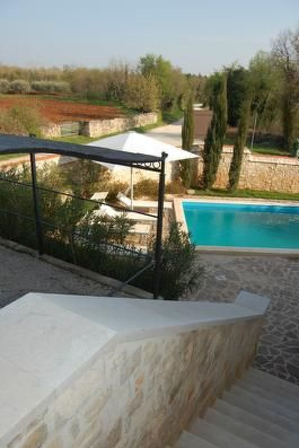 A pool area with a stone wall, a covered seating area, and a clear view of the pool.