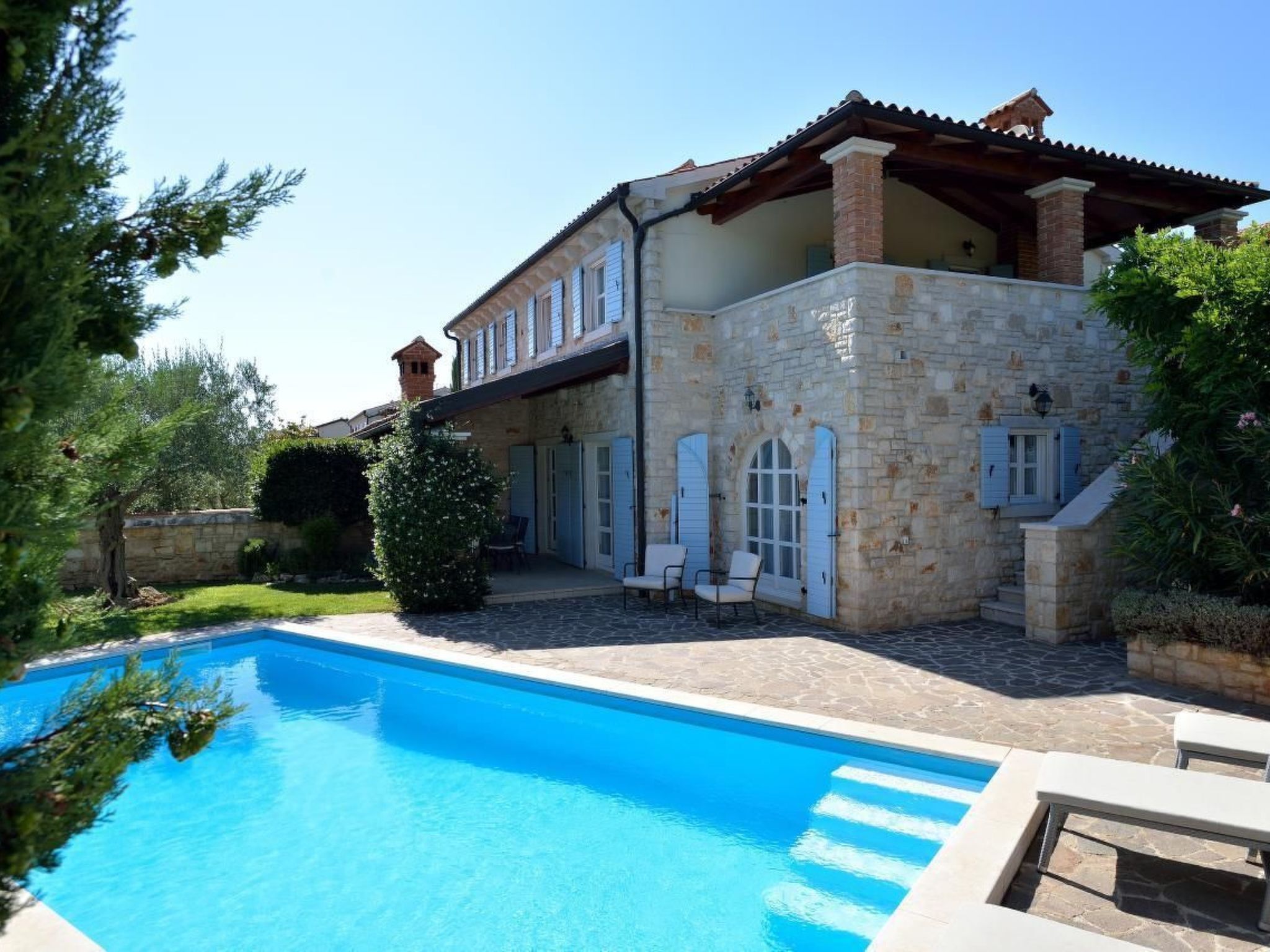 Un edificio de piedra con piscina, mobiliario de exterior y una pequeña torre.
