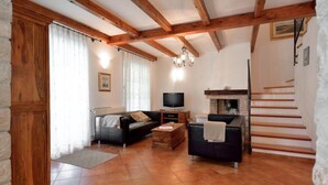 A living room with a fireplace, wooden beams, a TV, and a staircase. - Villa Maslinova Grana by Interhome (Poreč/Tar)