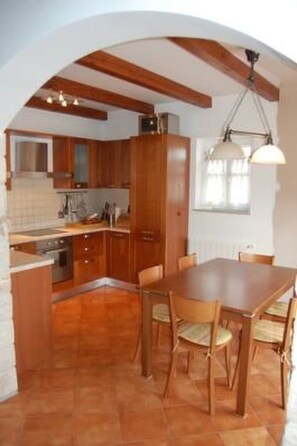 Una cucina con mobili in legno, un tavolo da pranzo con sedie e una lampada a sospensione.