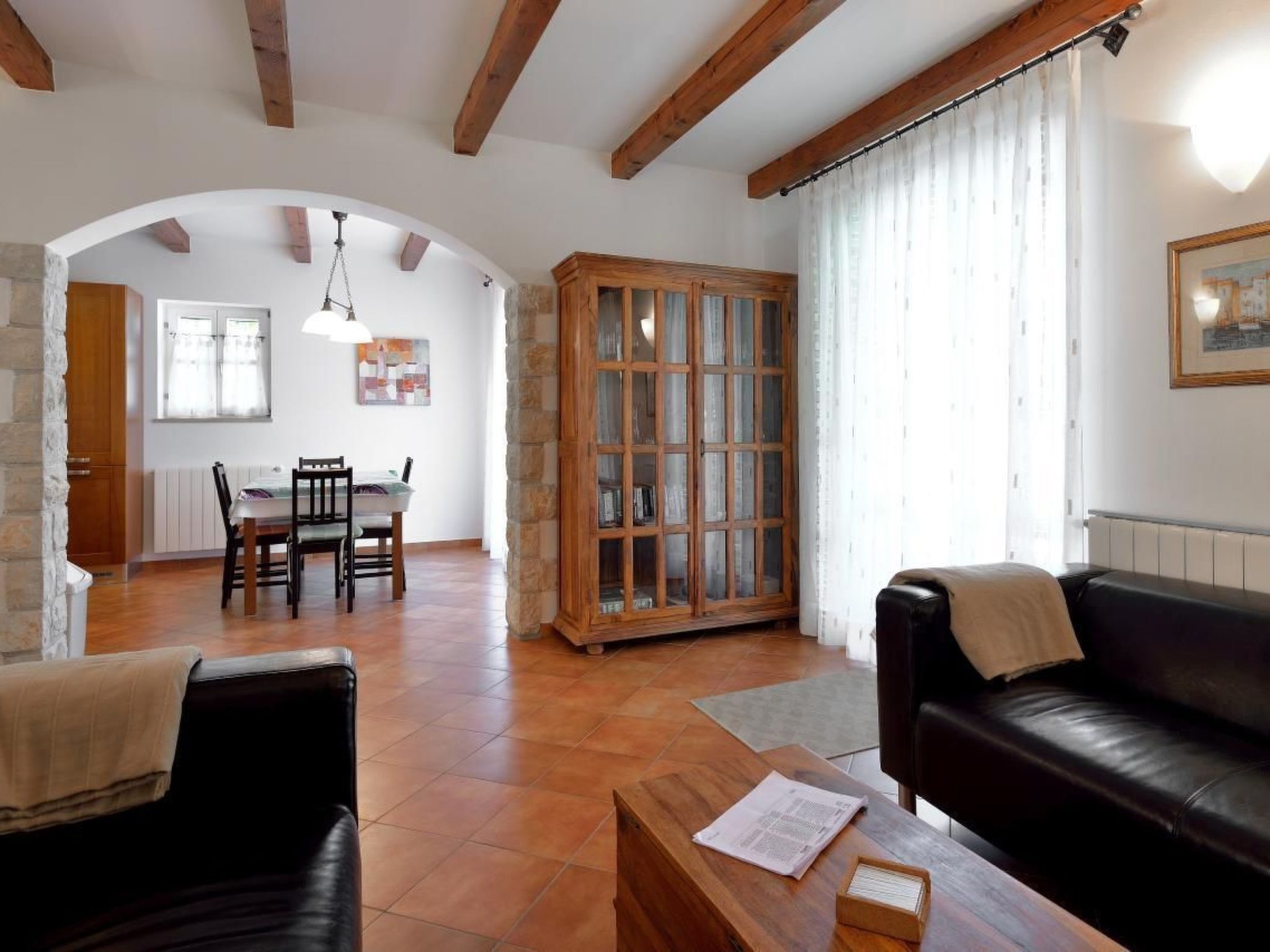 Un soggiorno con un divano in pelle nera, un tavolino in legno e una zona pranzo con tavolo e sedie.