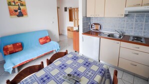 Eine kompakte Küche mit Essbereich, einem blauen Sofa und einem Bild an der Wand.