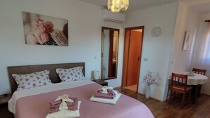 A bedroom with a bed, a bedside table, a mirror, a clock, and a dining area with a table and chairs. - Studio "Silva" mit Terrasse by Interhome (Novigrad (Istra))