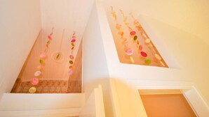 Eine Treppe mit einem gemusterten Boden und einer Reihe bunter, runder Dekorationen, die von der Decke hängen.
